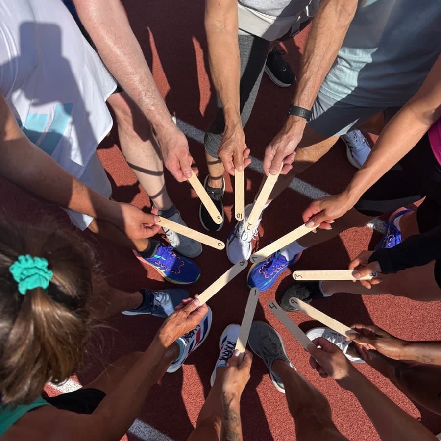 Runners on a track holding numbered sticks in a circle